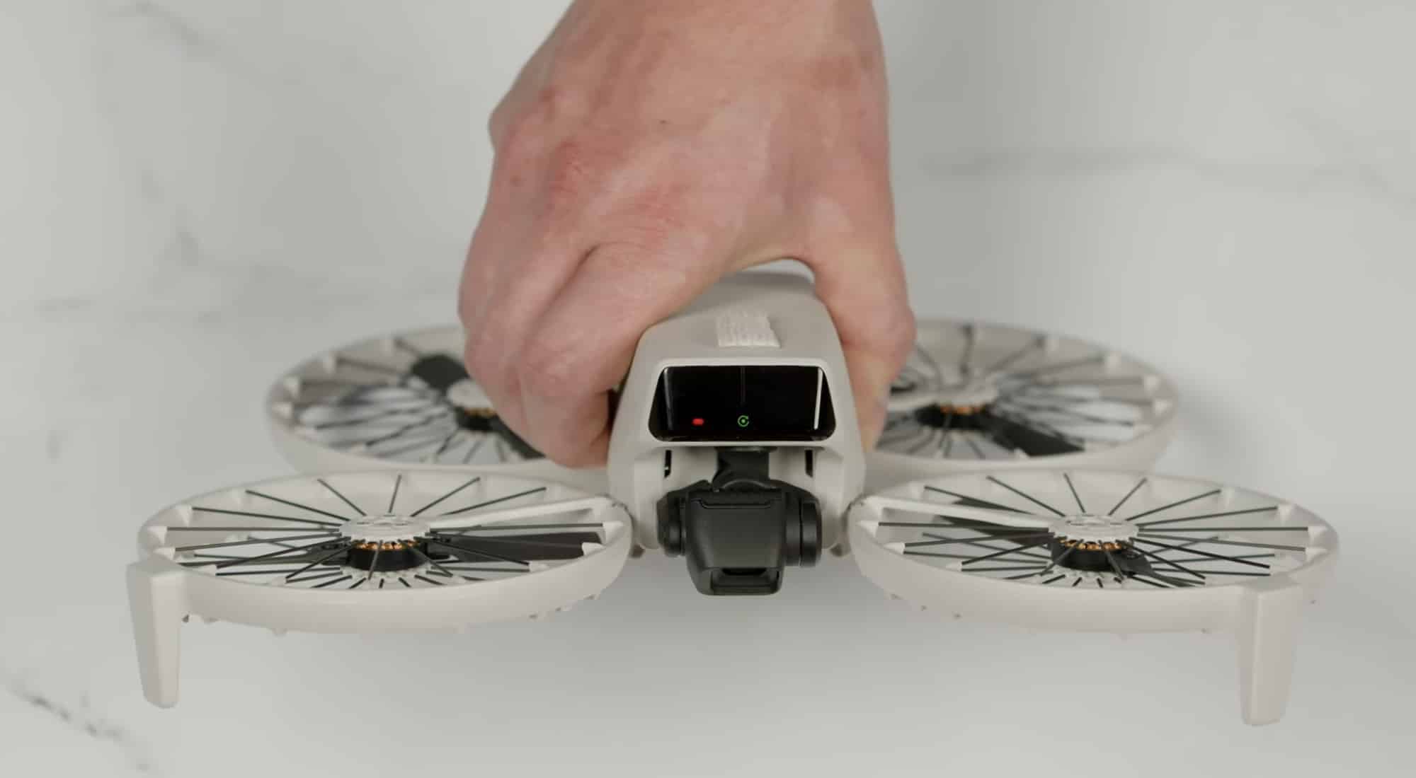 Hand setting the unfolded DJI Flip down on a white marble tabletop.