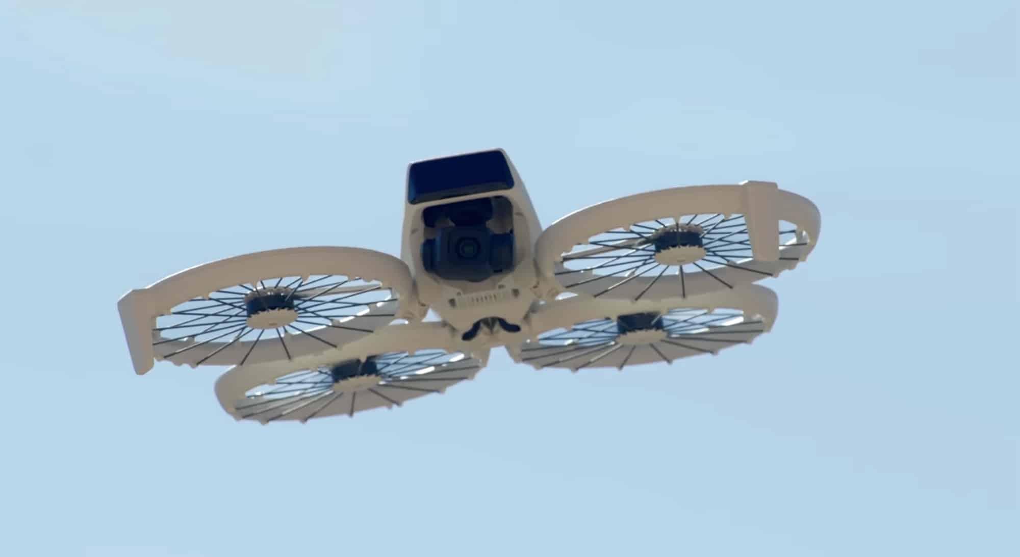 DJI Flip hovering against a clear blue sky with all four cages unfolded.