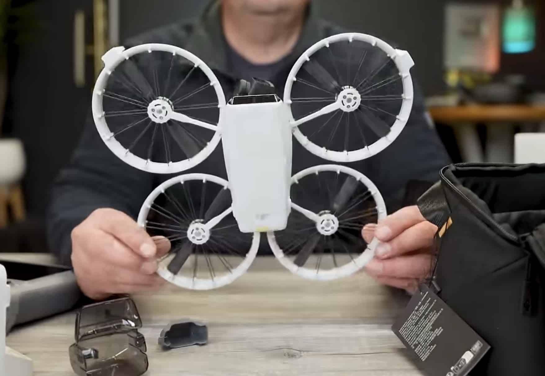 Reviewer spreads the four caged propeller guards of the DJI Flip at a desk.