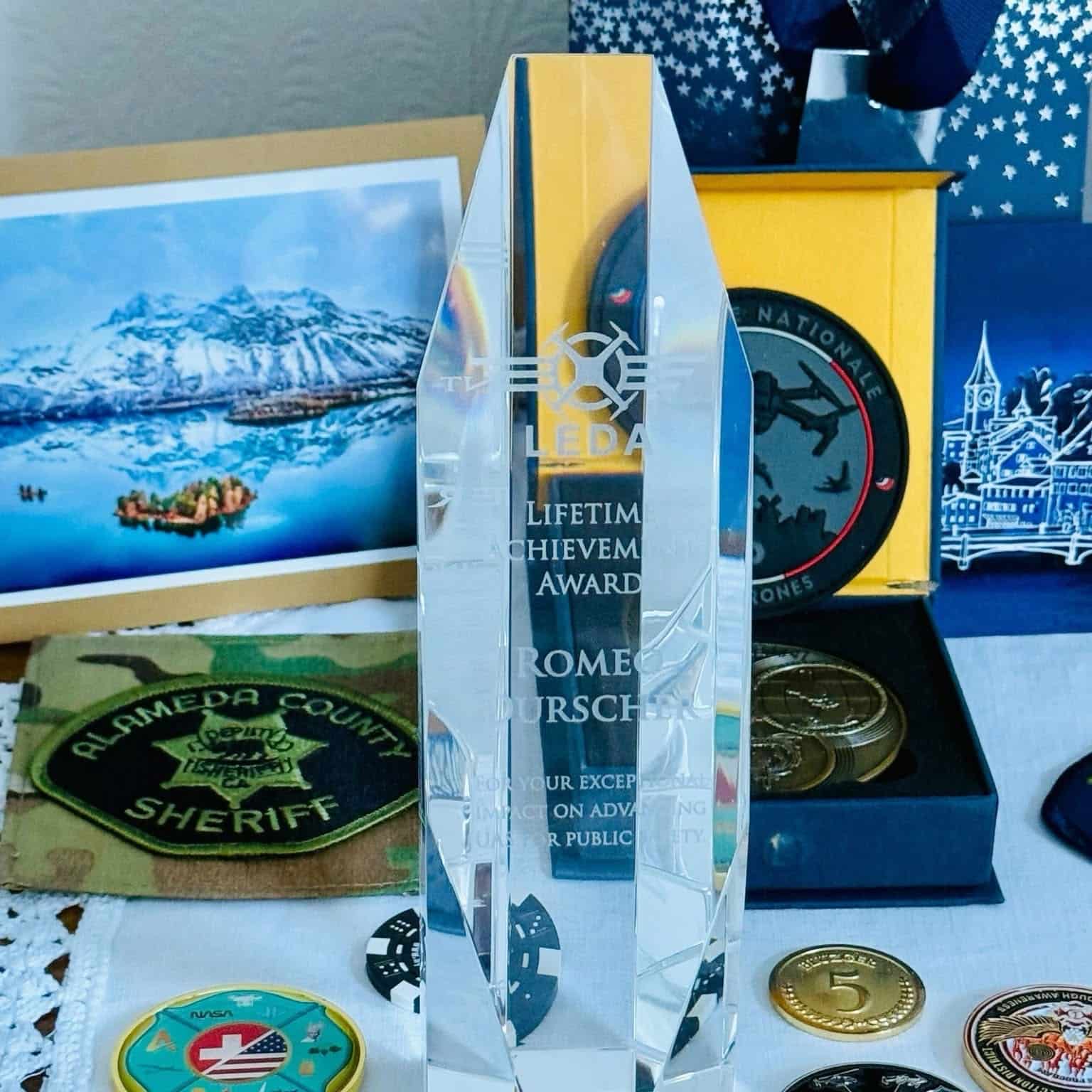 The crystal LEDA award standing among agency patches and challenge coins.