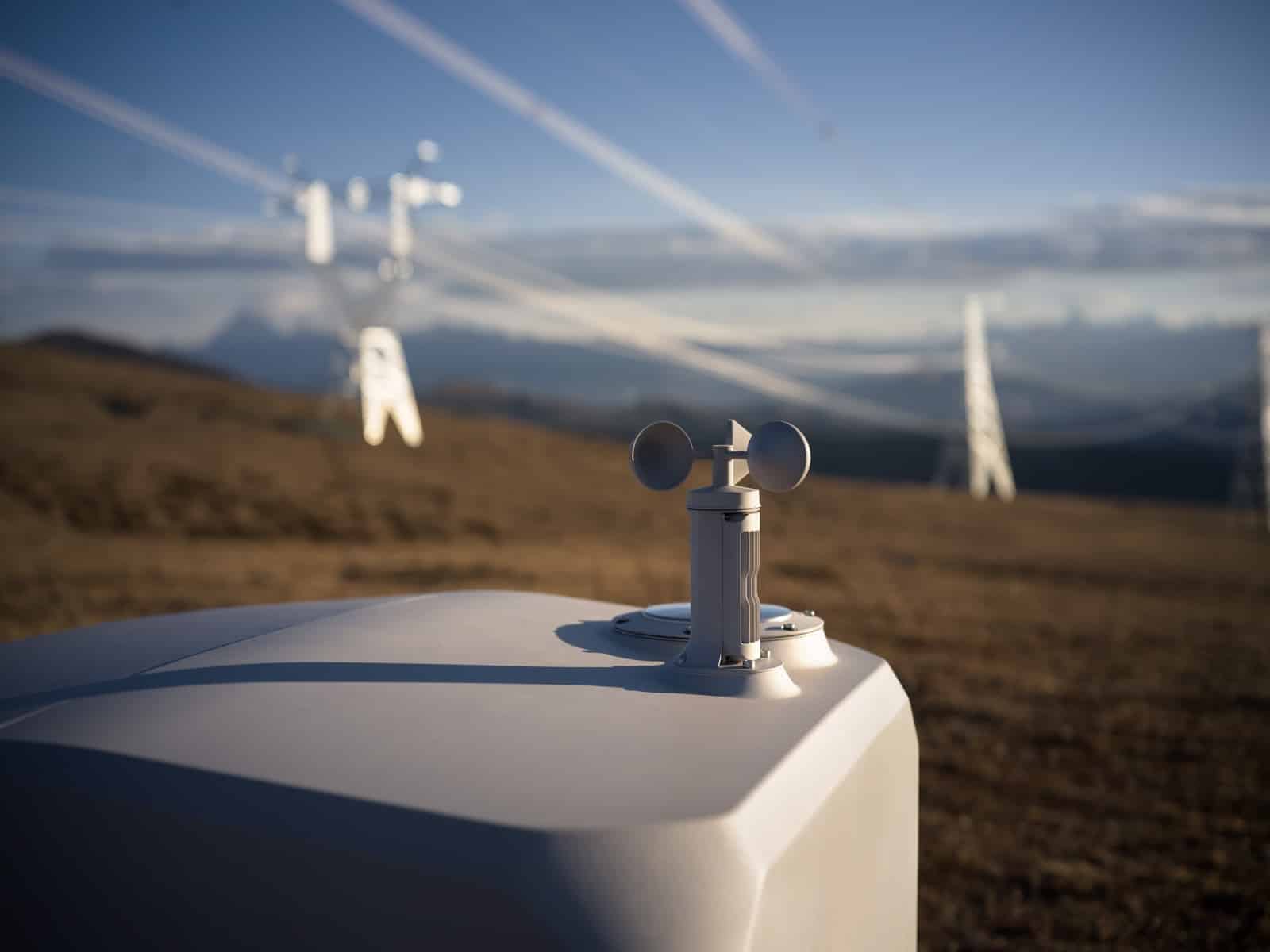 Wind sensor atop a closed white dock with transmission pylons in the haze.