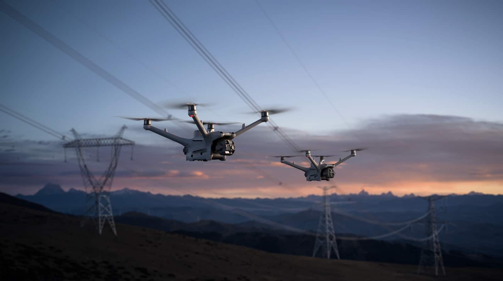 Two drones inspecting a line together as pink sunset clouds fill the sky.