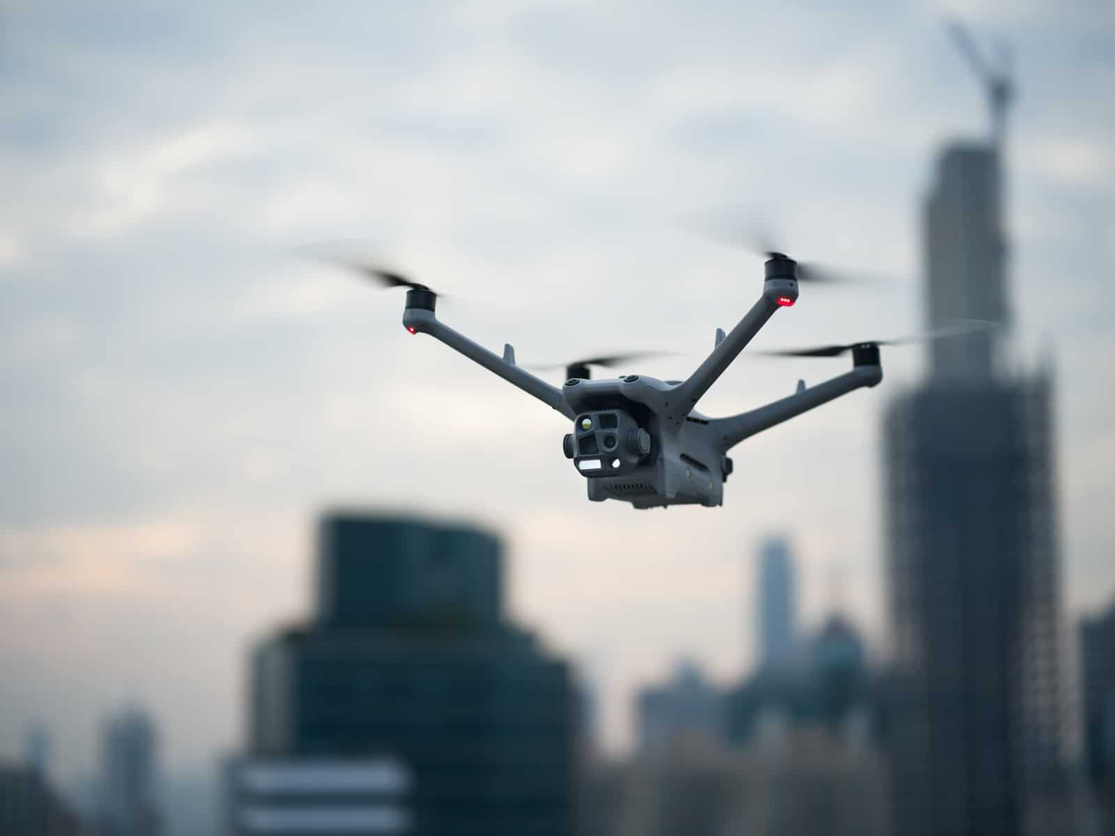 Drone hovering in front of an out-of-focus skyline with a construction crane.