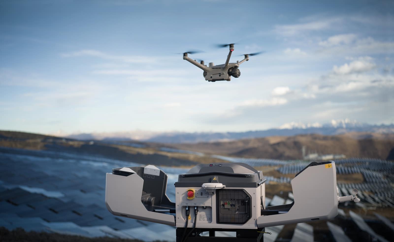 Drone climbing away from an open white dock overlooking a vast solar farm.