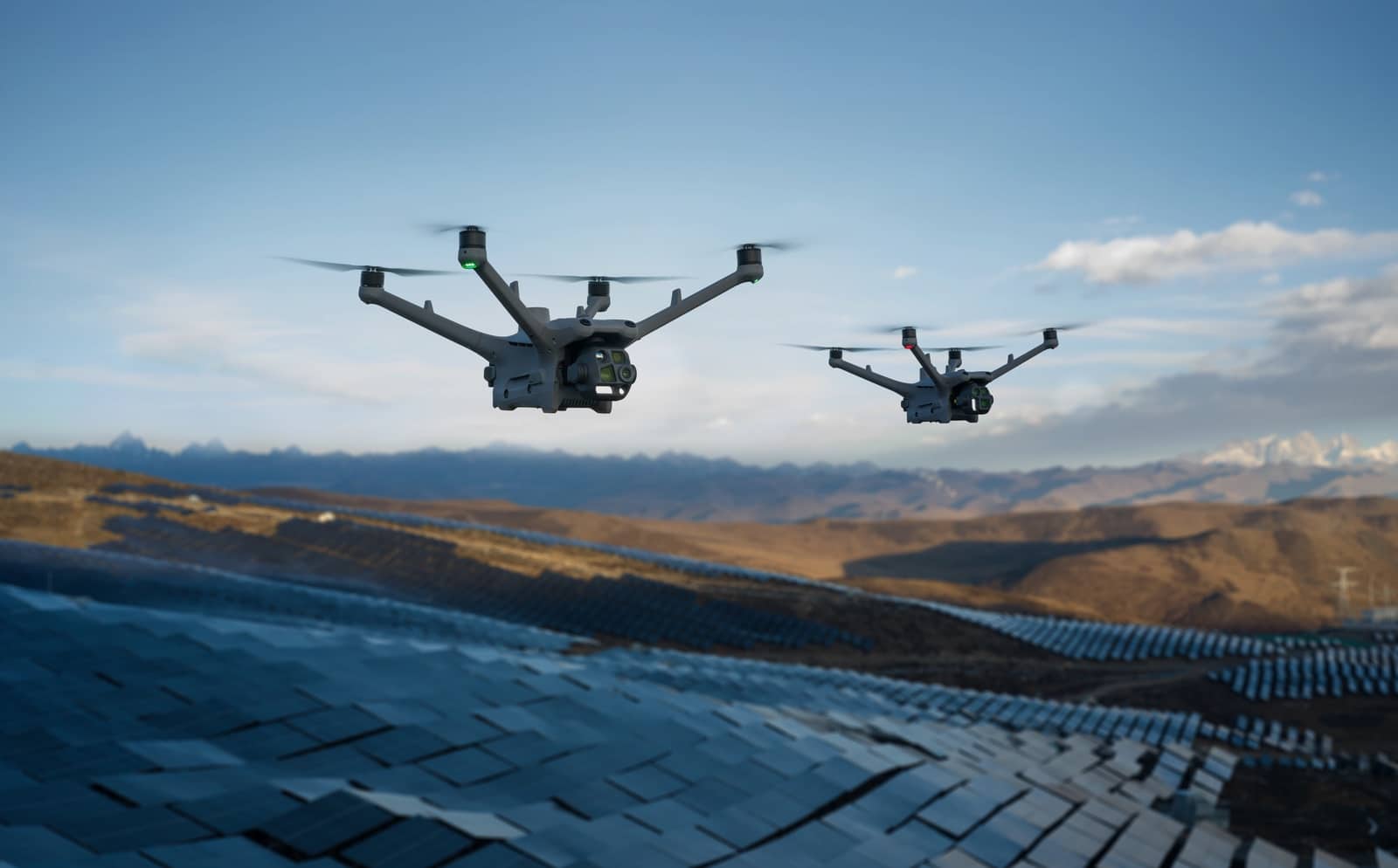 Two drones flying in tandem over the solar plant at dusk.