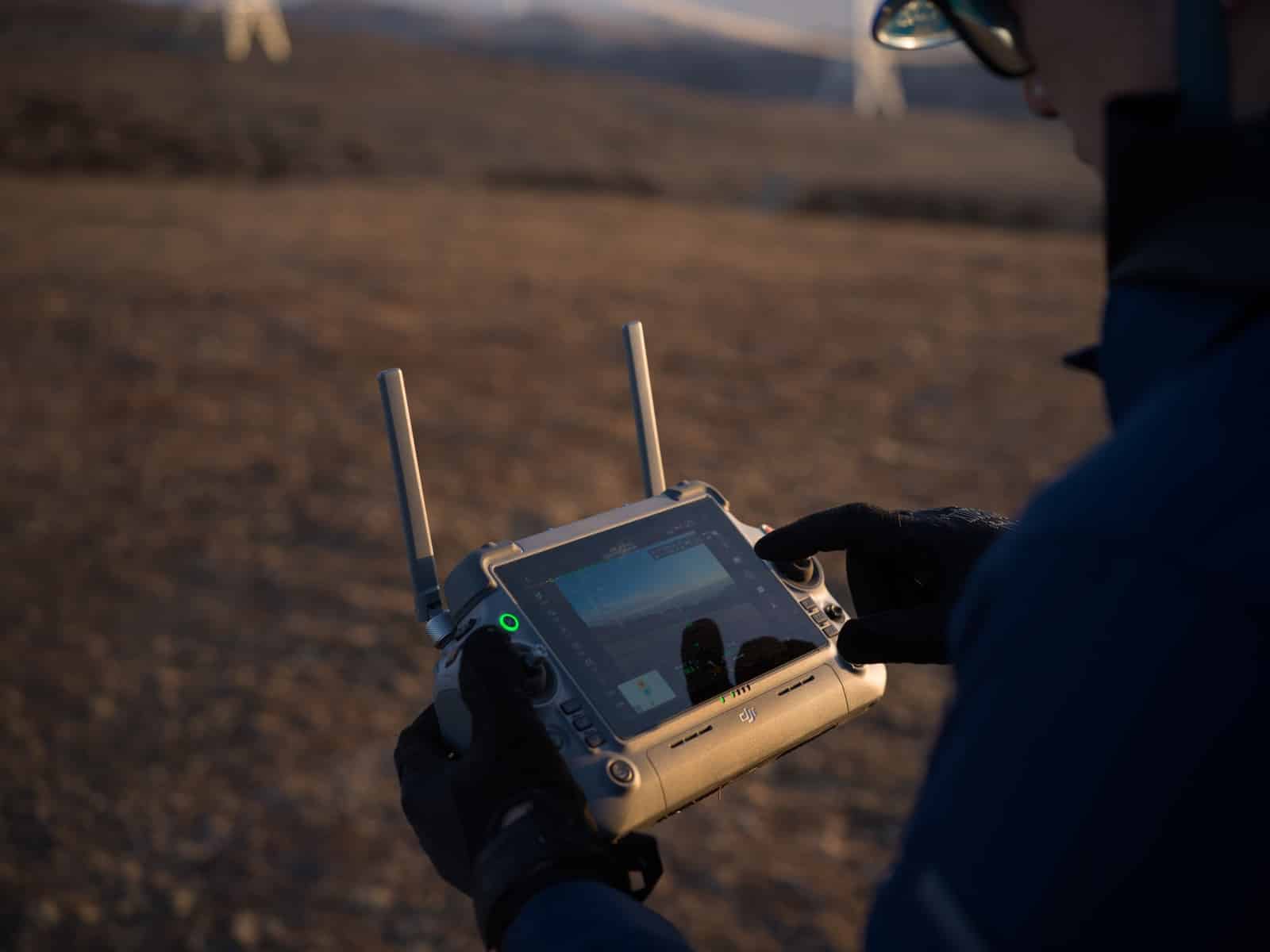 Gloved hands holding the dual-antenna enterprise controller out in the field.