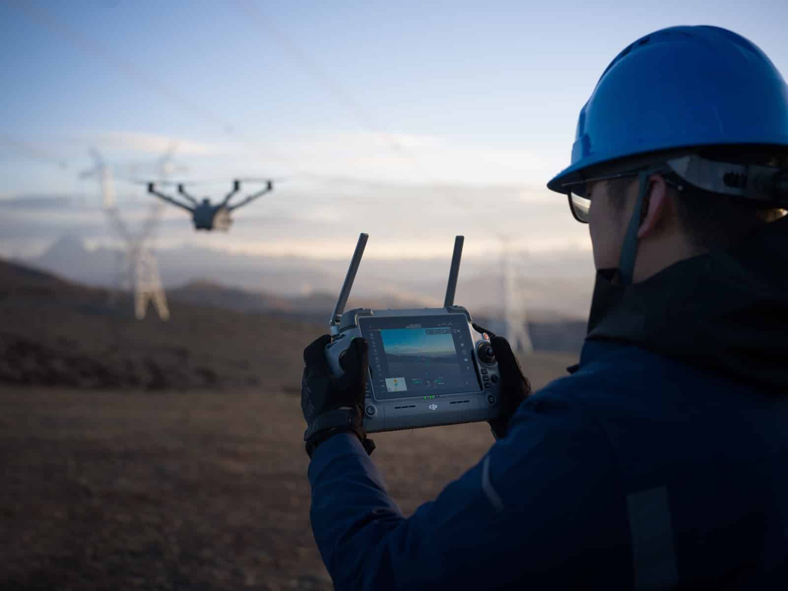Worker in a blue hard hat flying the drone with the enterprise controller.