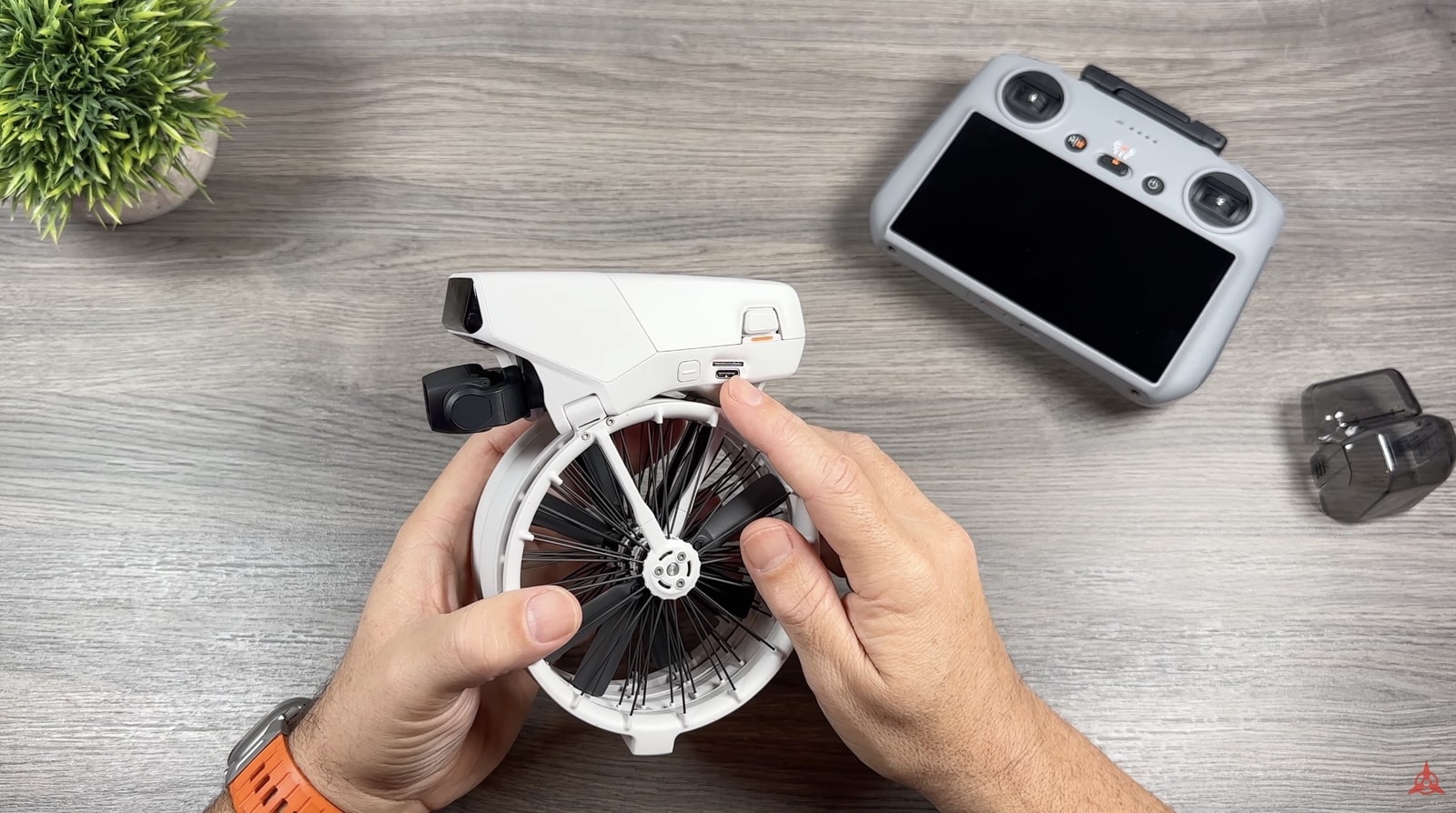 Hands folding out an arm of the DJI Flip beside its controller and battery.