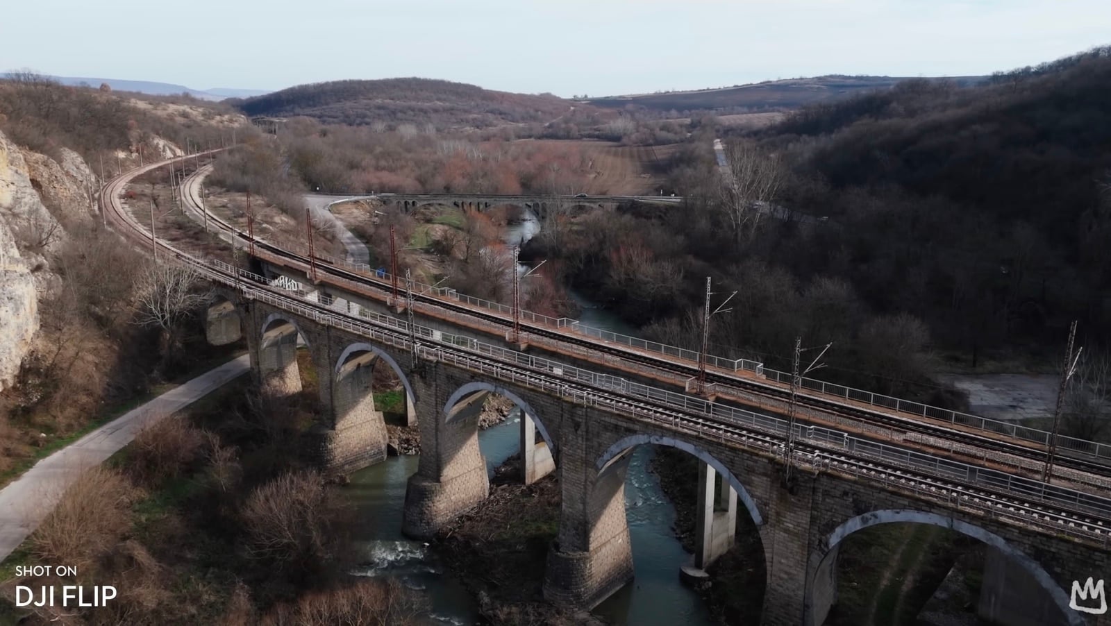Aerial view of a stone railway viaduct crossing a wooded river valley.