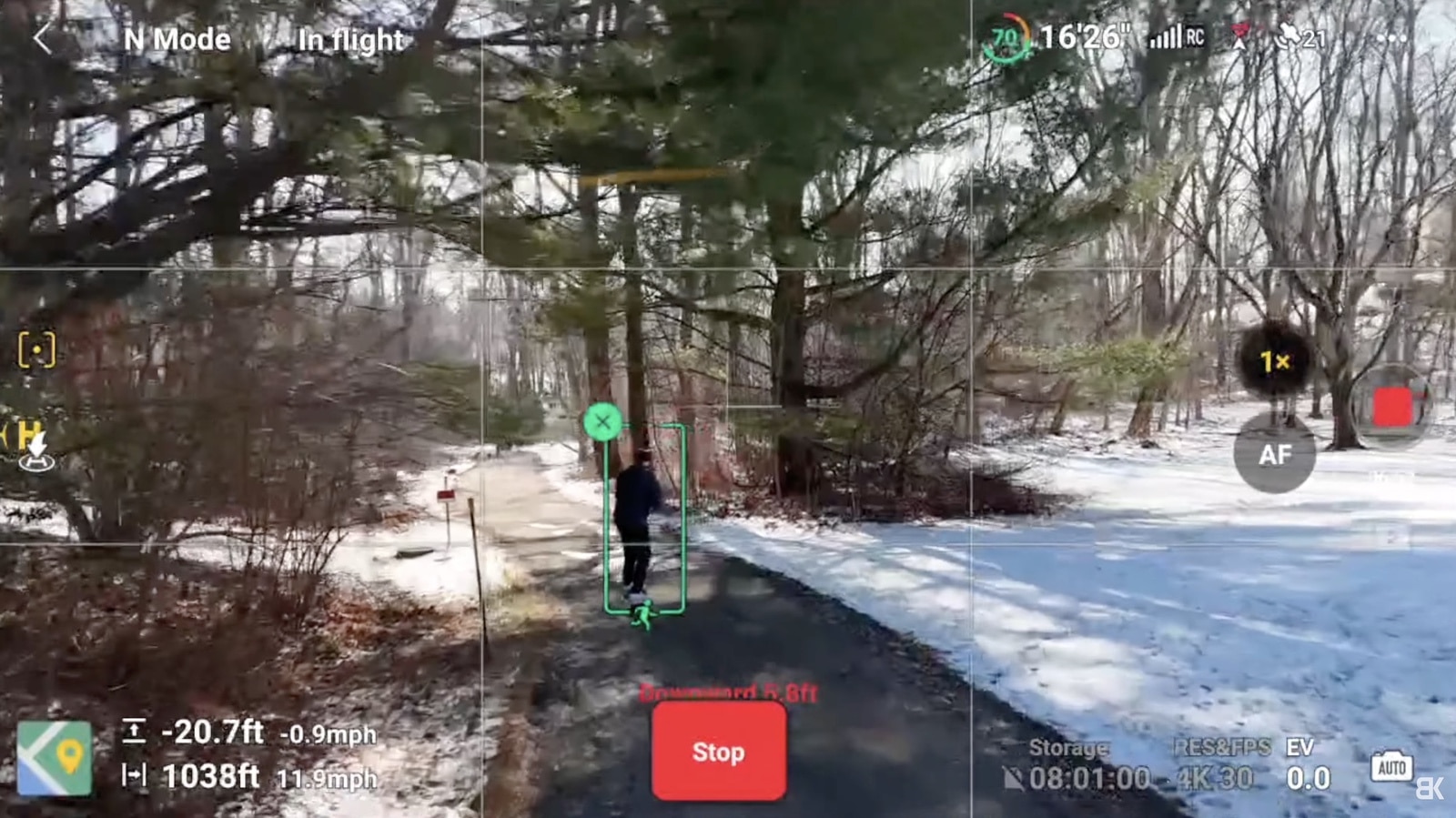 DJI Fly ActiveTrack box locked onto a person walking a snowy woodland trail.