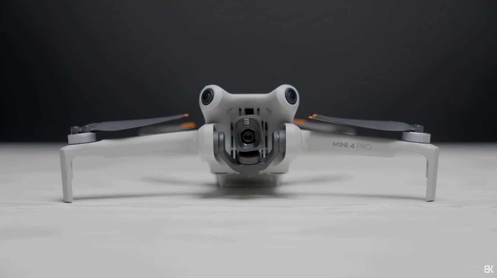 DJI Mini 4 Pro unfolded on a plain gray studio backdrop.