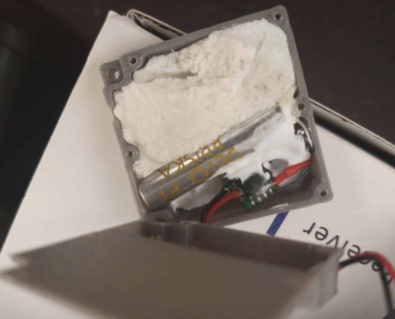 Close-up of the module showing white explosive filler and a small circuit board.