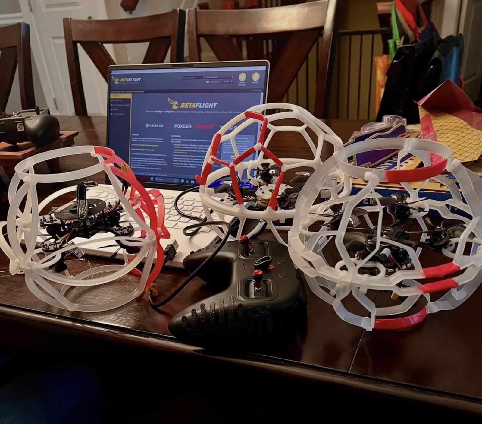 Drone soccer craft in protective exoskeletons beside a laptop running Betaflight.