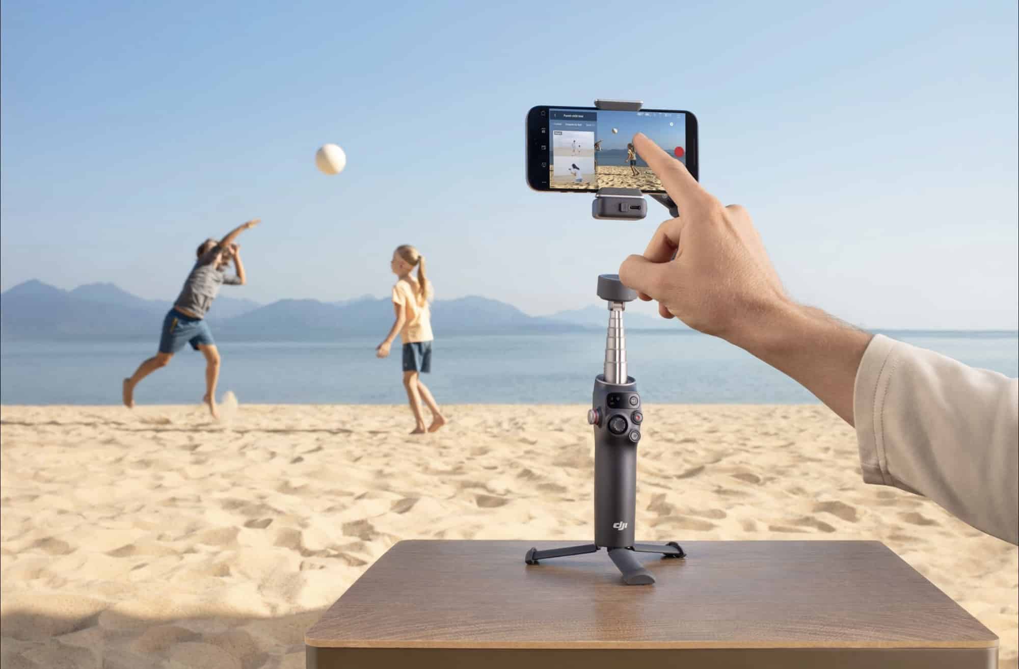 A finger taps the phone screen to start tracking two people on the beach.