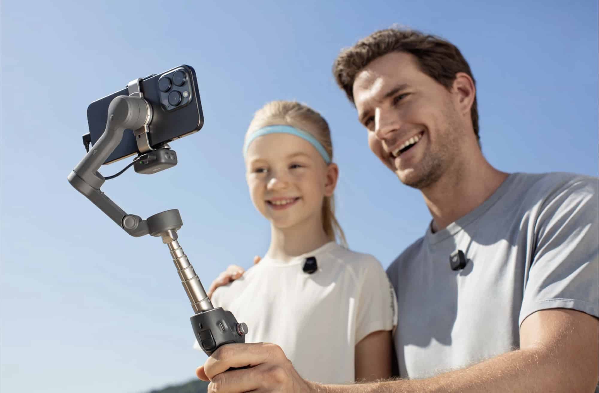 A man and girl wearing clip-on microphones smile beside the extended gimbal.