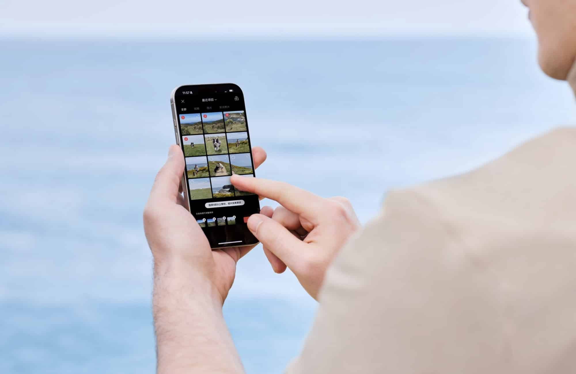 Hands scroll a grid of clips in the editing app beside the water.