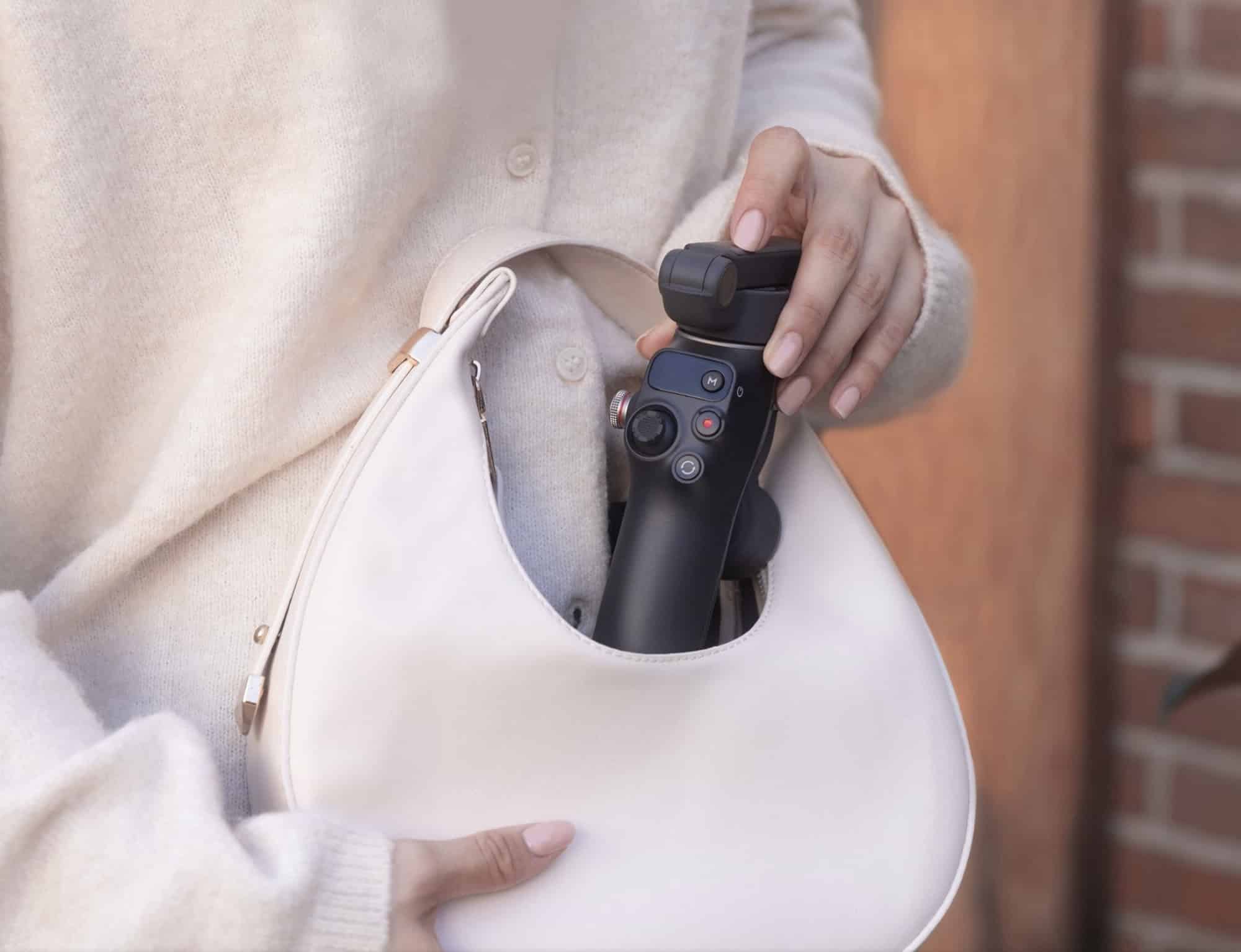 A folded gimbal slides into a white shoulder bag.