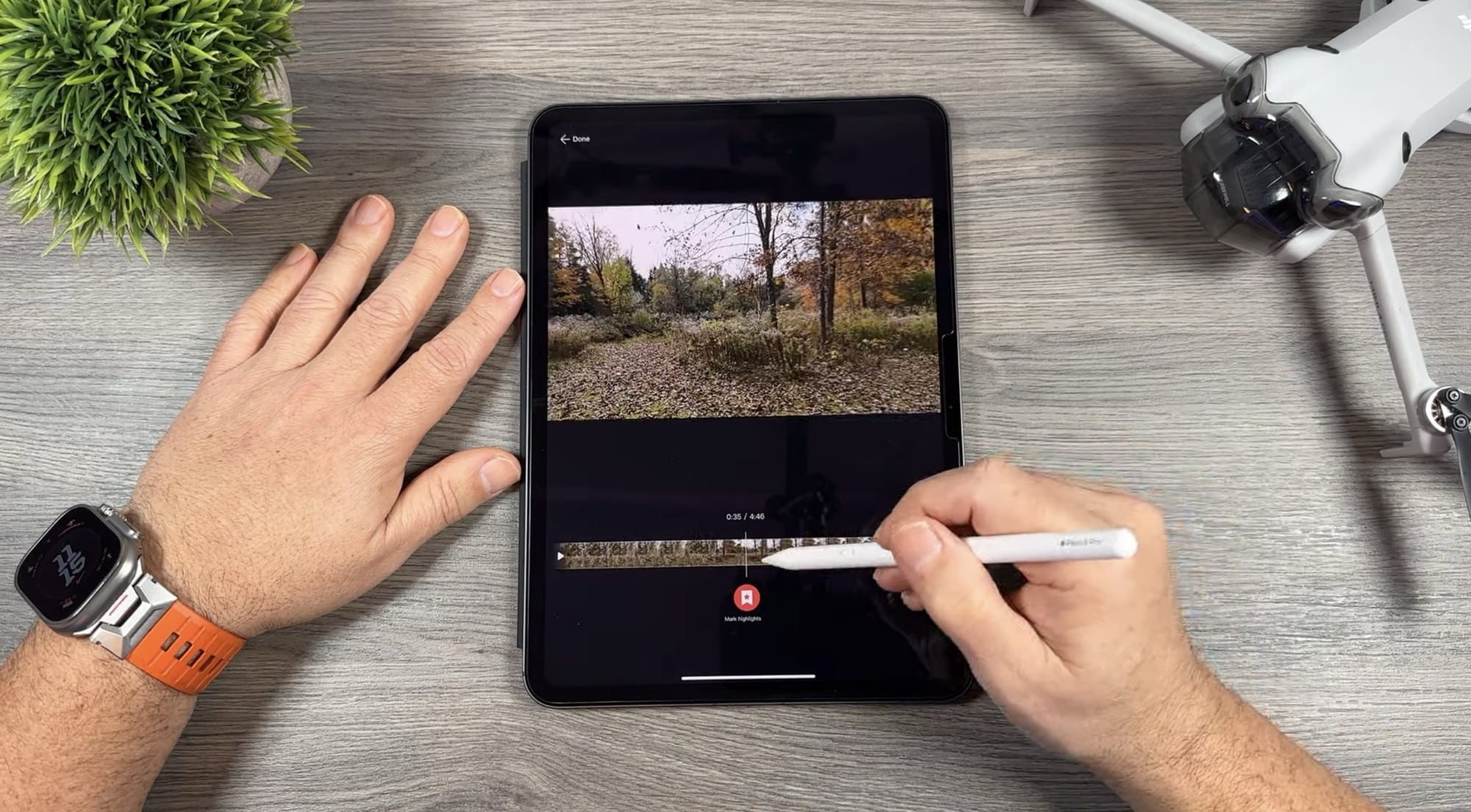 Stylus trims a clip on a tablet timeline beside the folded drone.