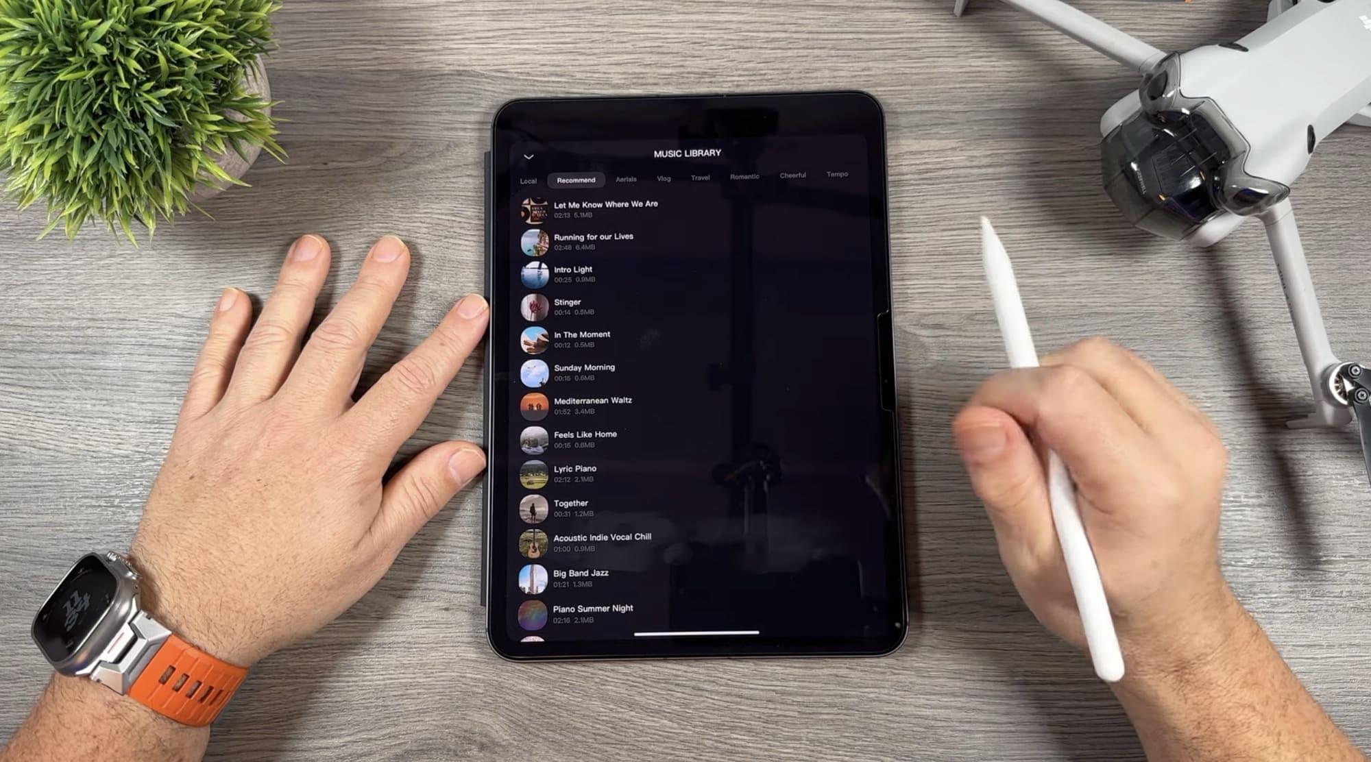 Tablet shows the music library list while a stylus hovers nearby.