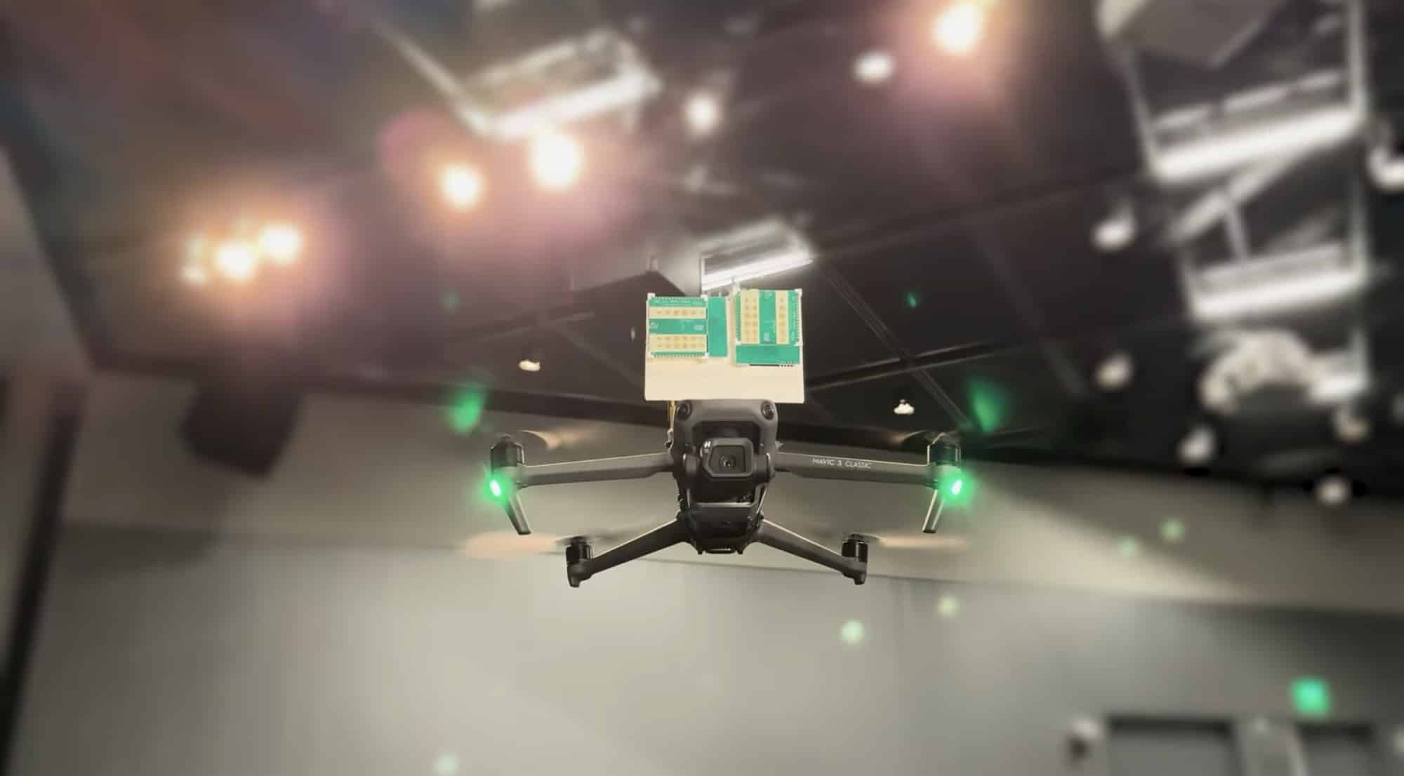 Radar boards ride on top of a quadcopter hovering in a lit laboratory.