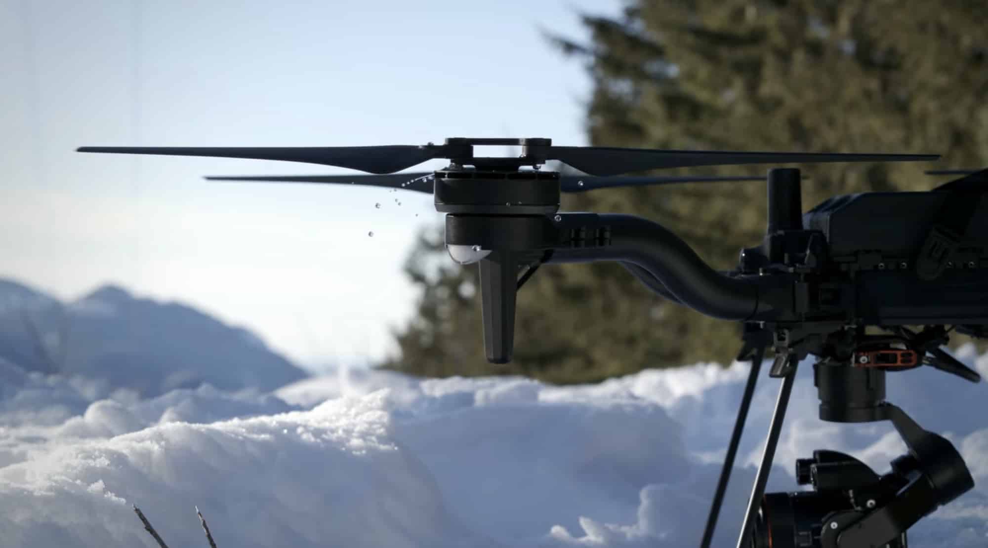 The Freefly Astro Max sits in deep snow with mountains rising behind it.