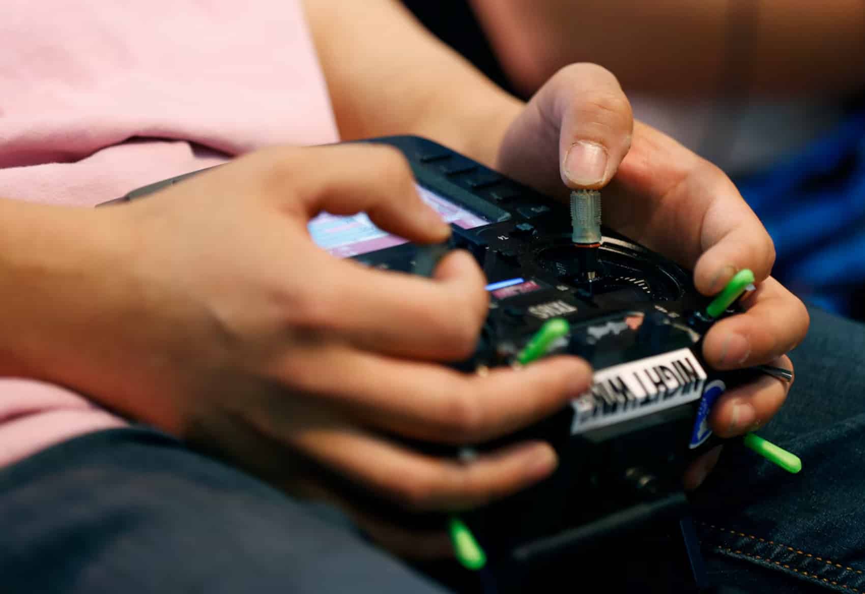 A young pilot's hands work the sticks of an FPV radio transmitter.