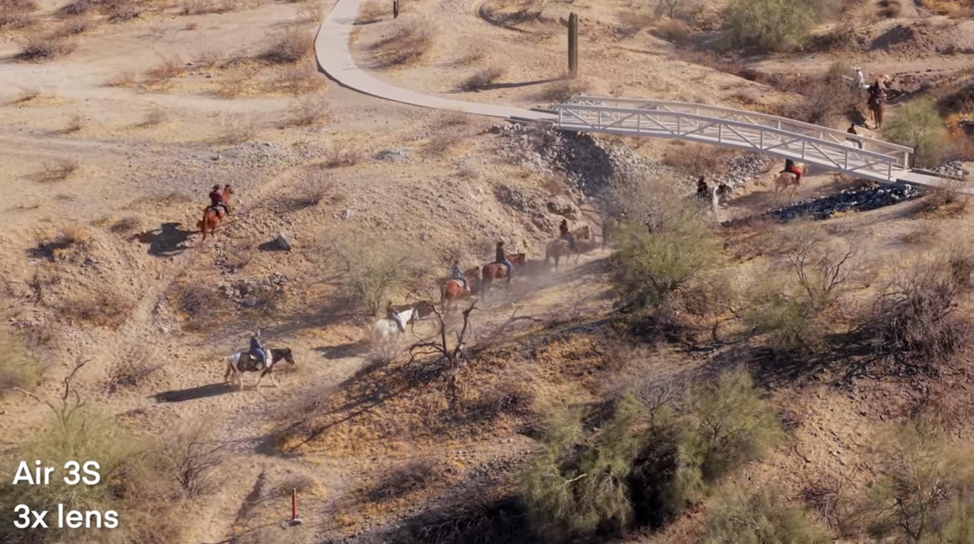 Aerial telephoto of horseback riders on a desert trail, marked Air 3S 3x lens.