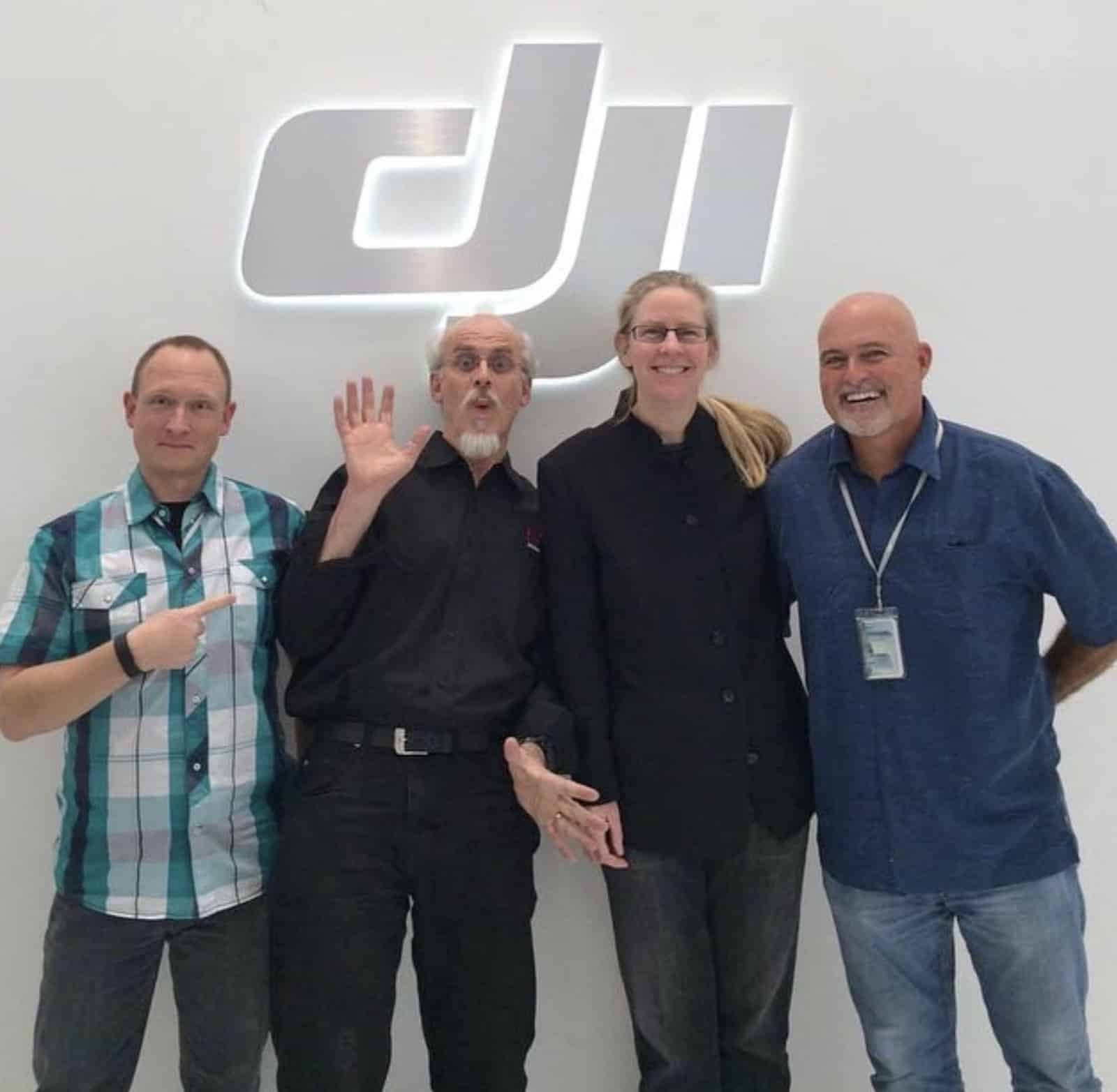 Four colleagues pose indoors under a backlit DJI wall logo.