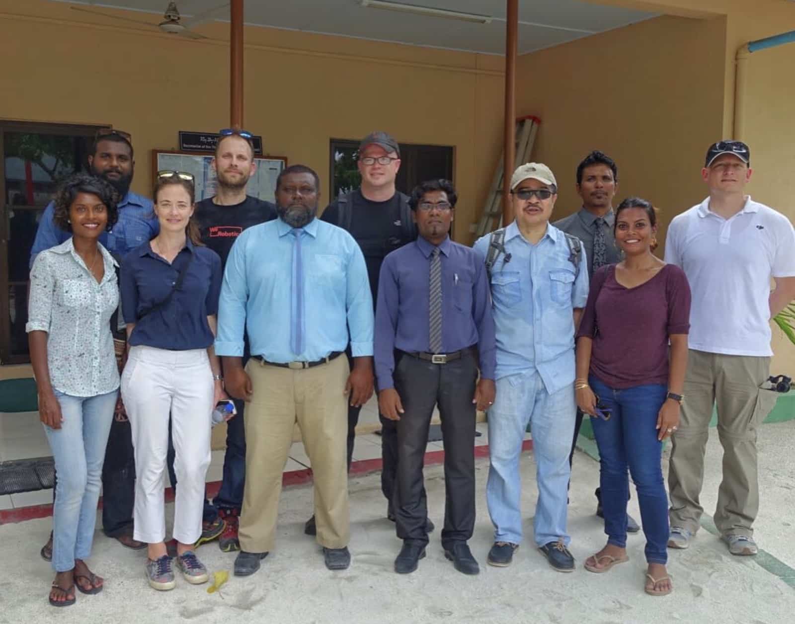 A dozen colleagues line up for a group portrait inside a tropical field office.