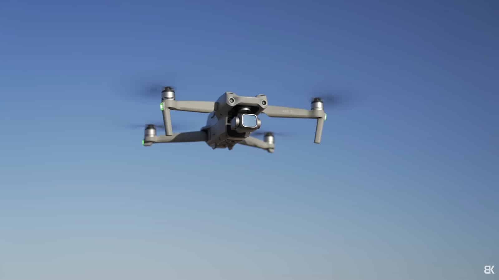 A quadcopter seen from below against a deep blue sky.