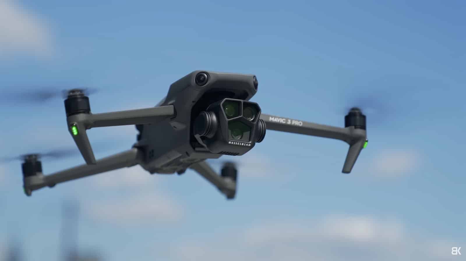 A Mavic 3 Pro banks in flight with its Hasselblad camera cluster forward.