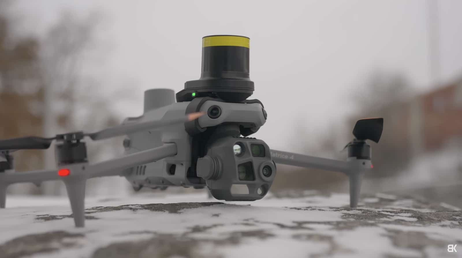 An enterprise drone with a yellow lidar module rests on snowy ground.