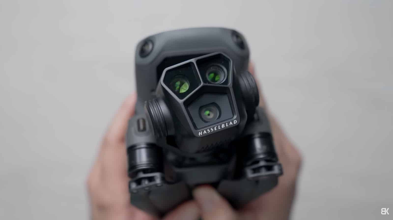 Hands hold a Mavic 3 Pro up close, showing three Hasselblad lenses.