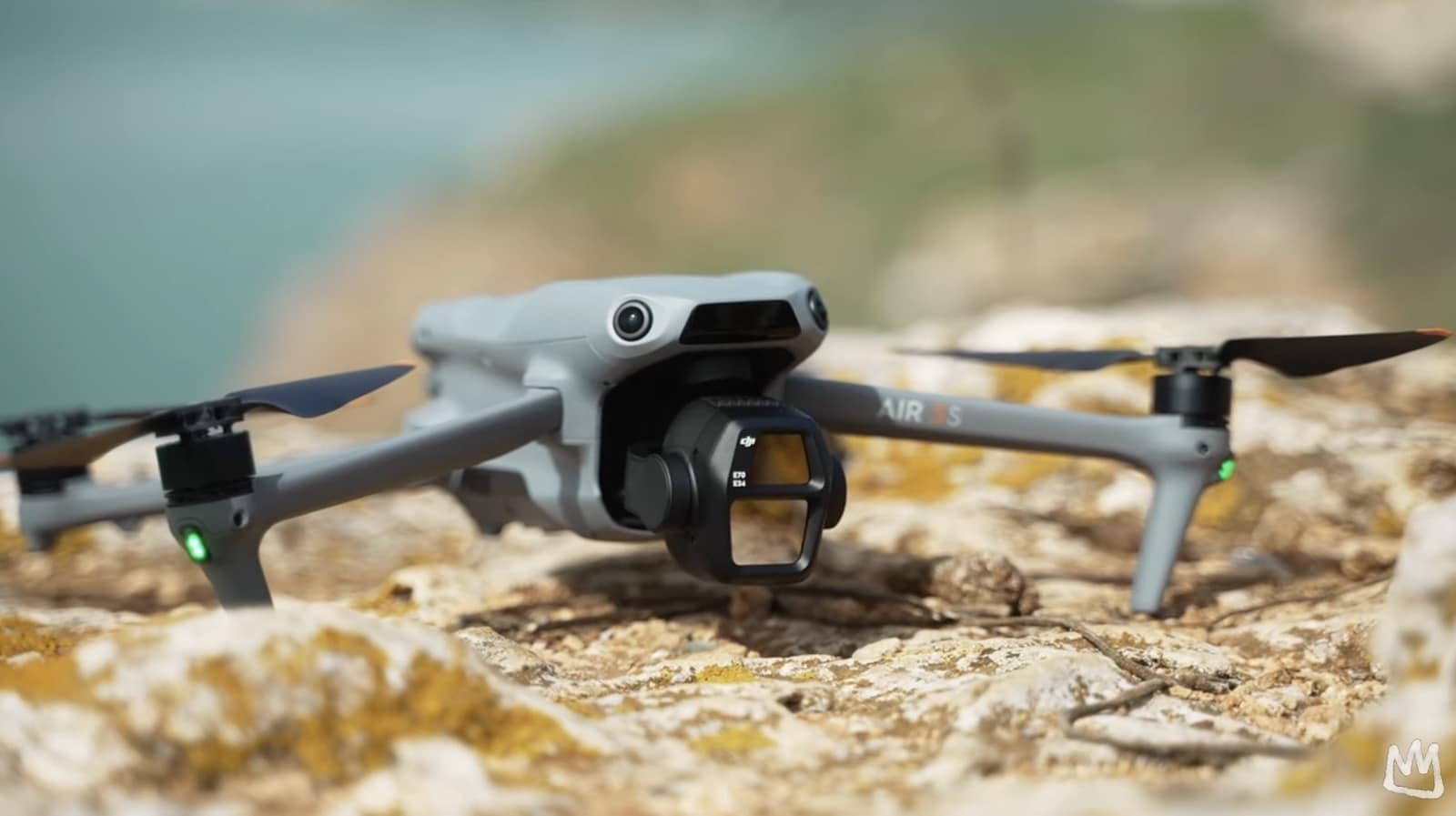DJI Air 3S resting on a lichen-covered rock above a distant coastline.