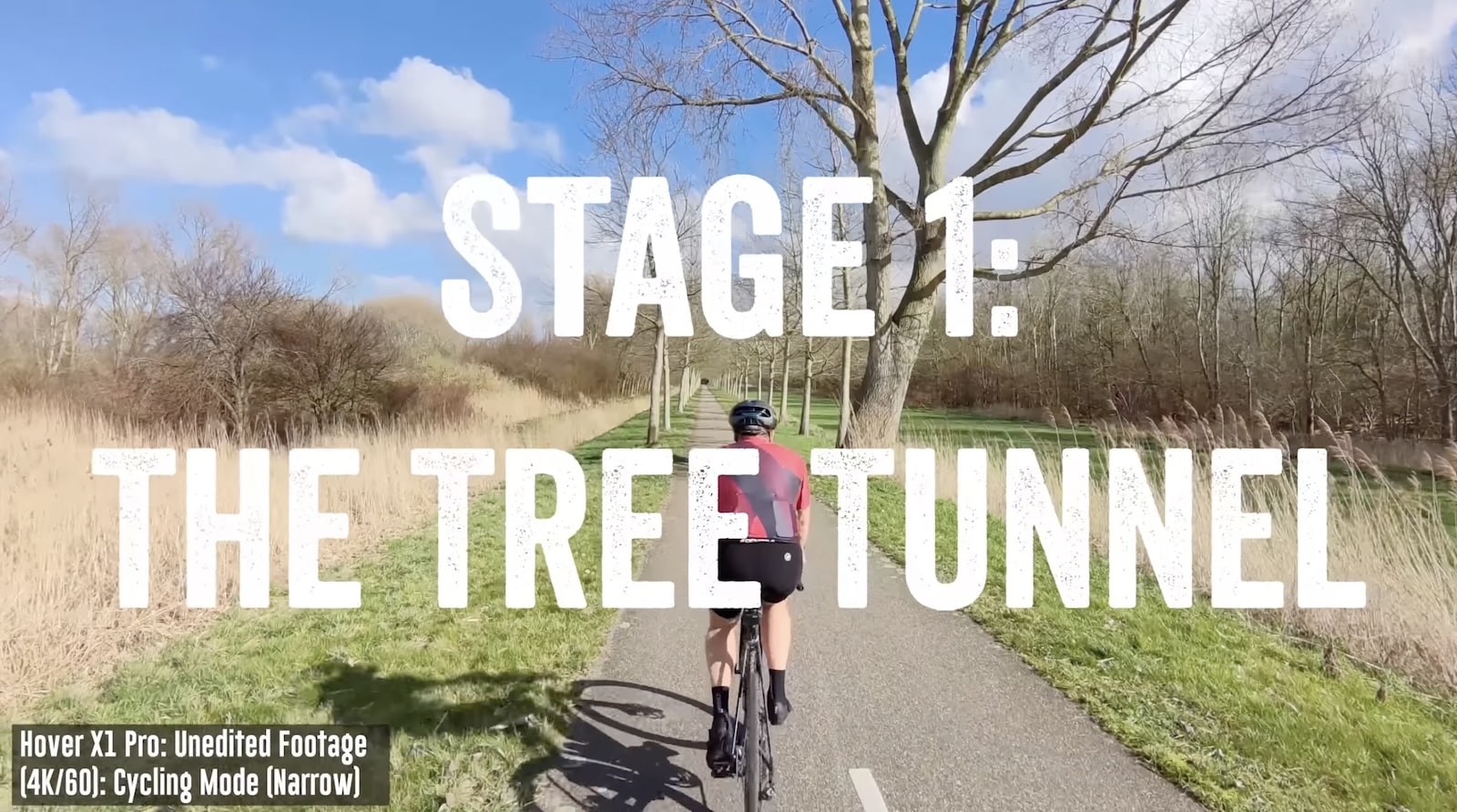 Stage 1 title card over unedited cycling footage through a bare tree tunnel.