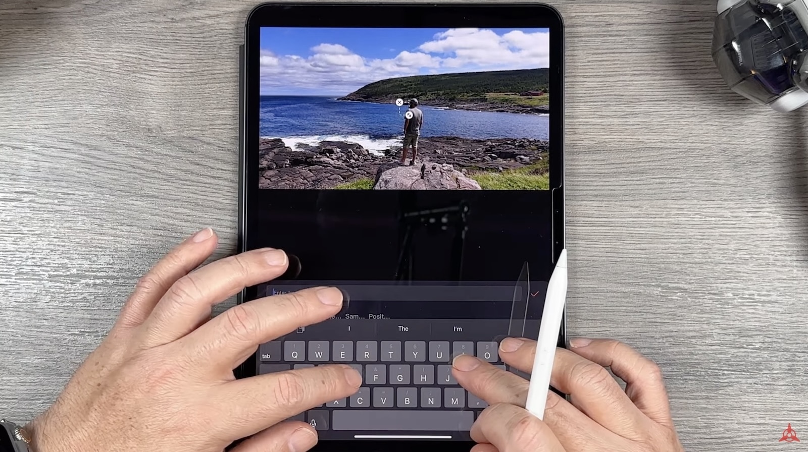 Tablet previewing a coastal drone clip above an attached keyboard during editing.