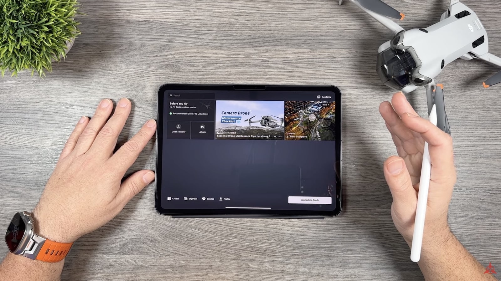 Overhead shot of hands at a tablet running the editing app beside a folded drone.