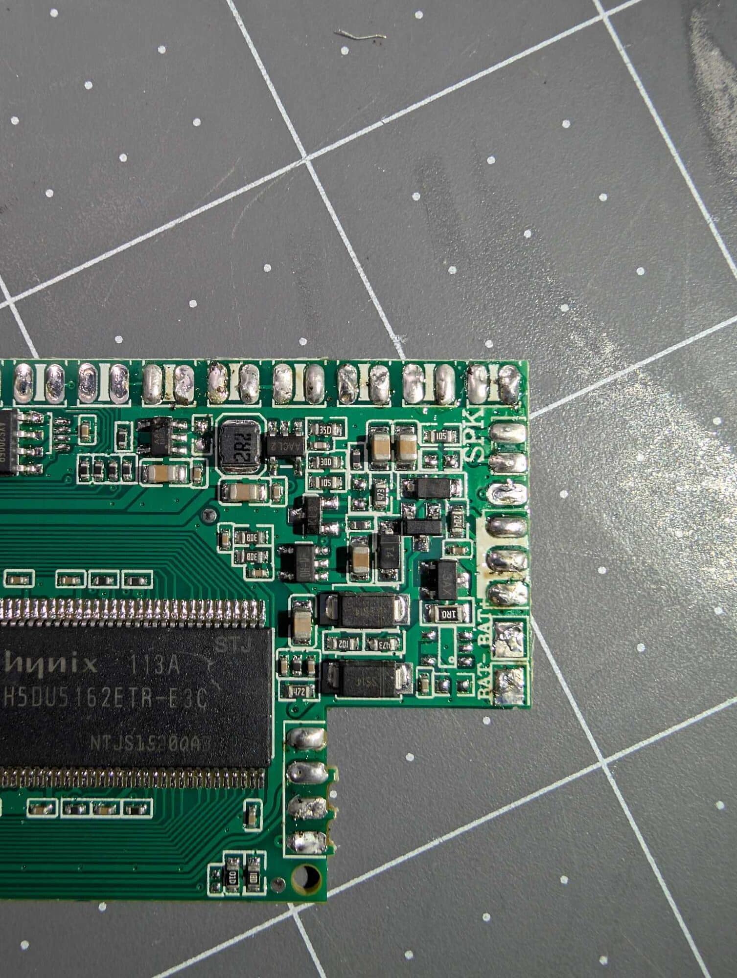 The mailer circuit board photographed on a gridded cutting mat, chips facing up.