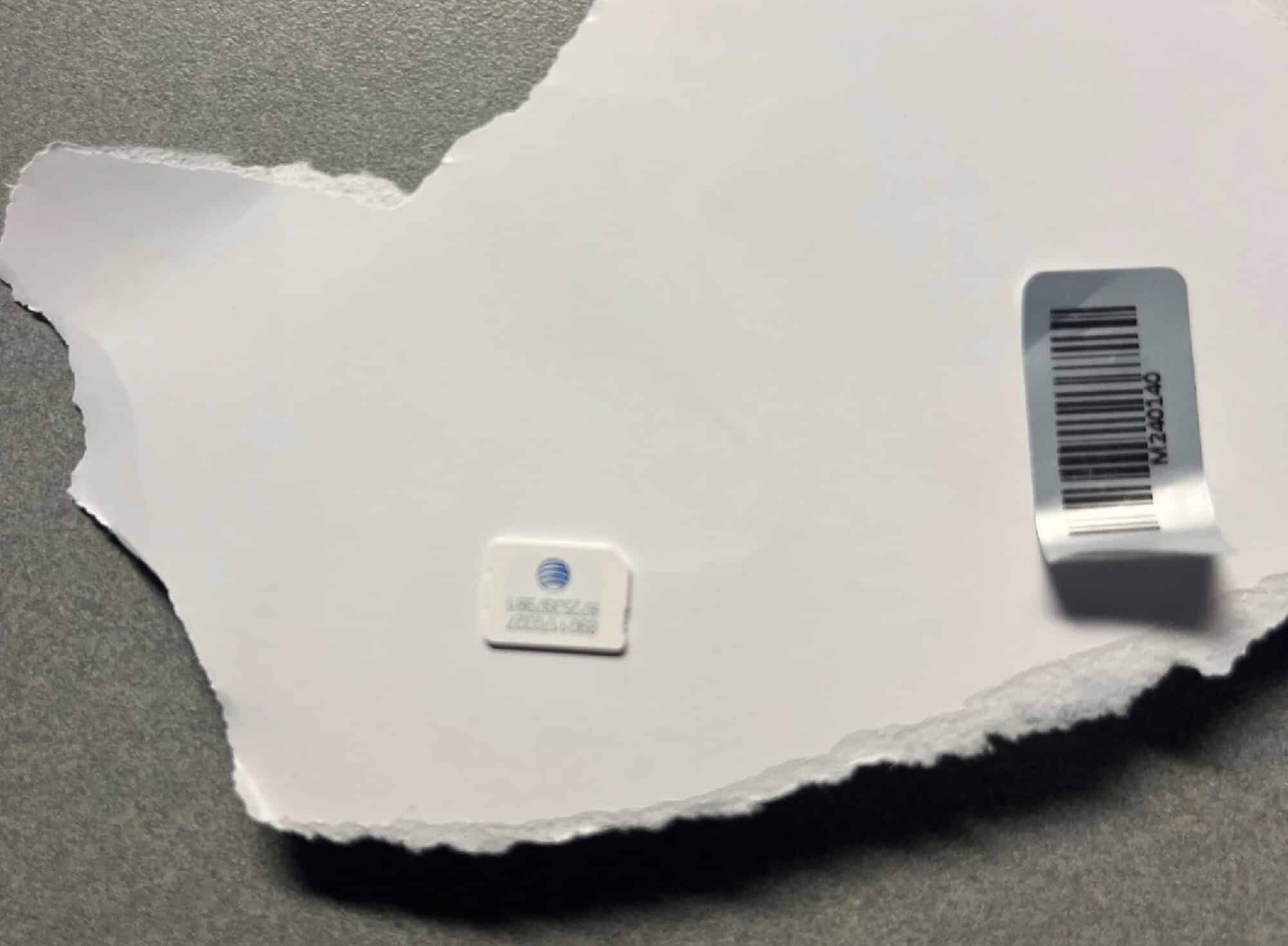 The torn-open mailer revealing an embedded AT&T SIM card and barcode label.