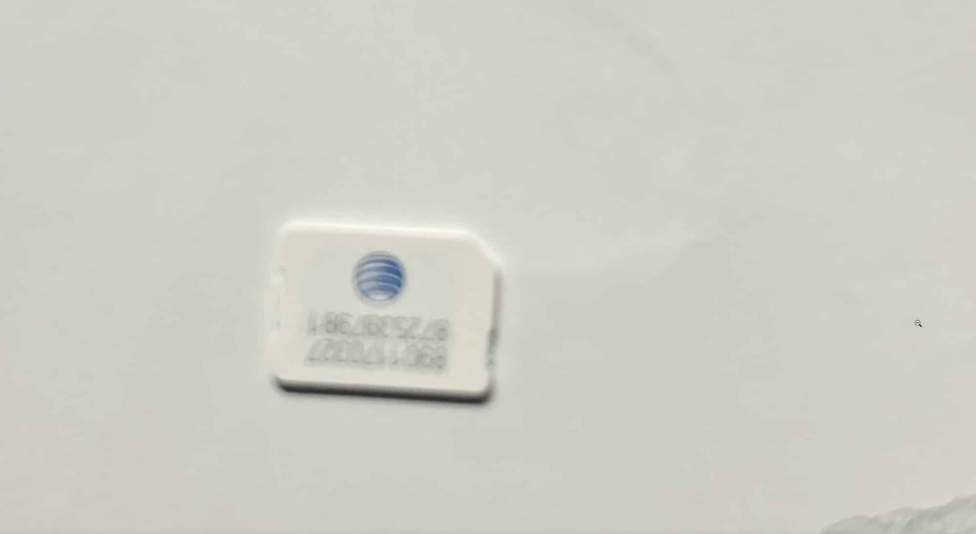 A small white AT&T SIM card photographed on a blank surface.