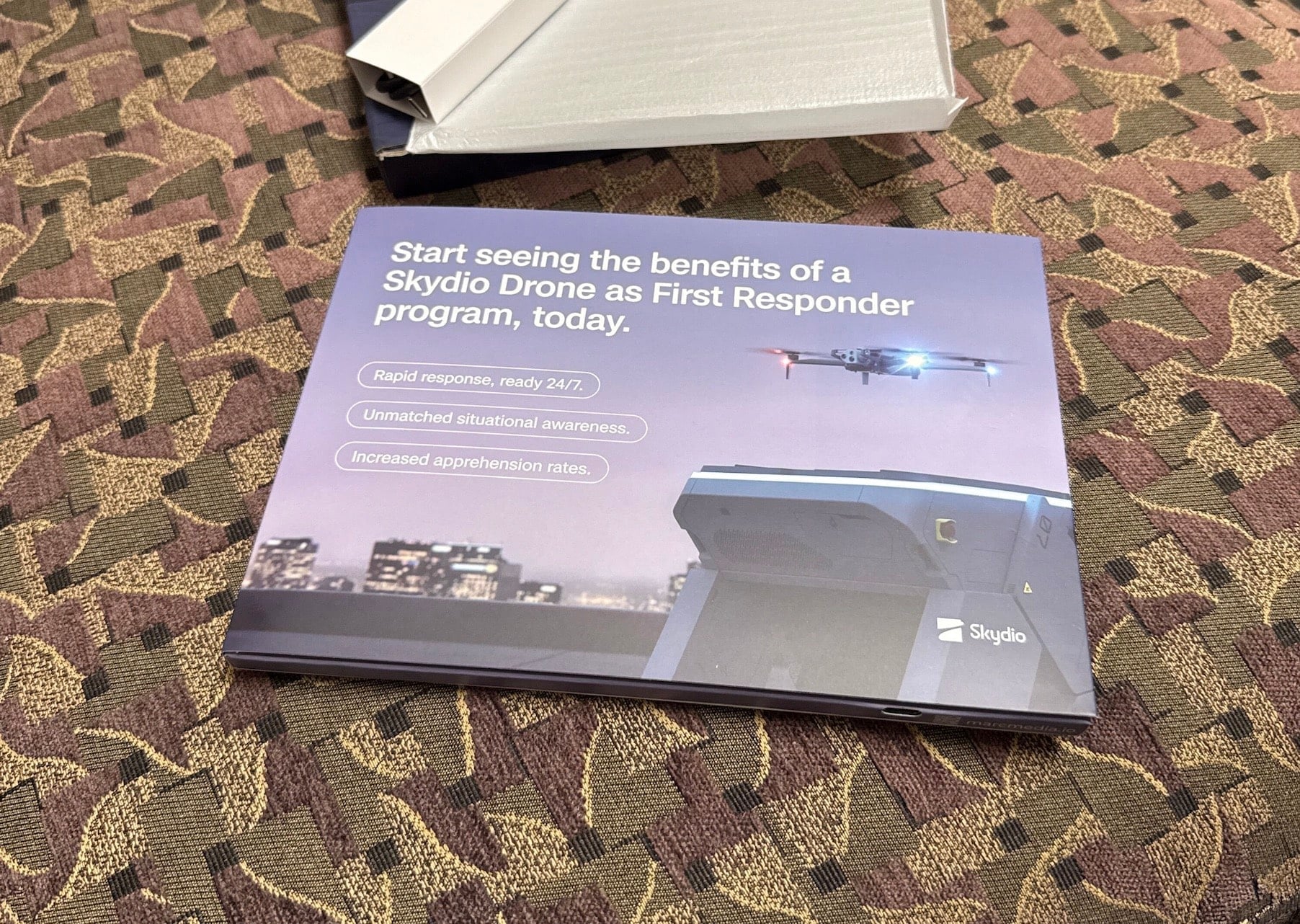 A video brochure pitching a drone first responder program lies on office carpet.