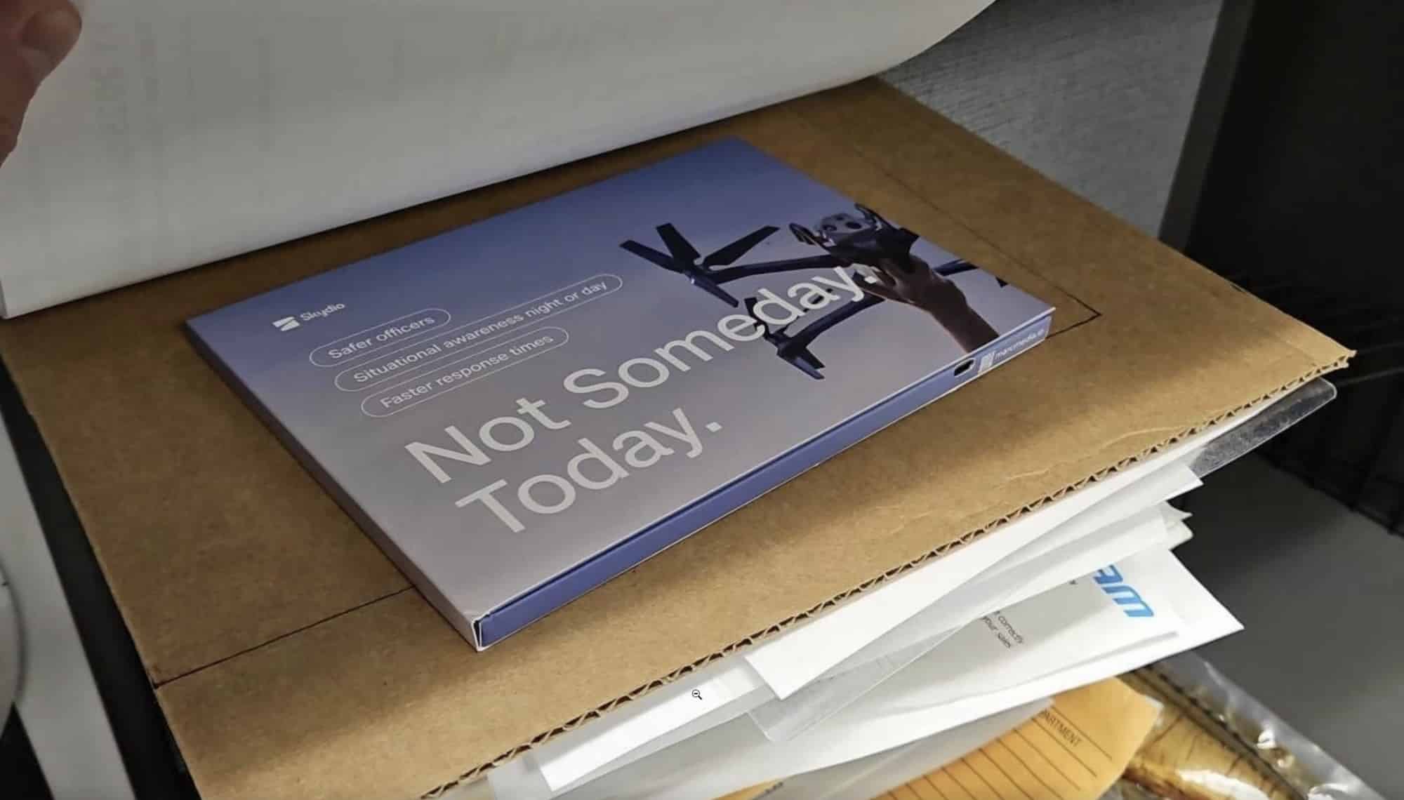 An opened cardboard mailer on a desk revealing a marketing card among other post.