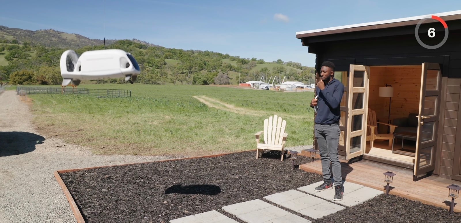 Host stands outside a small test cabin with a Zipline aircraft on the lawn.