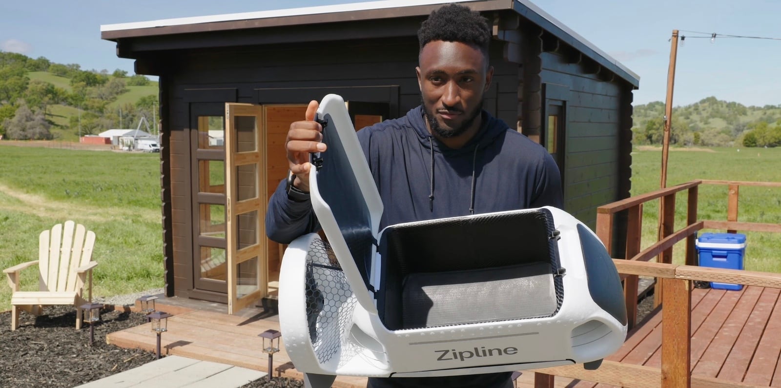 MKBHD holds a white Zipline P2 delivery aircraft on a home deck.