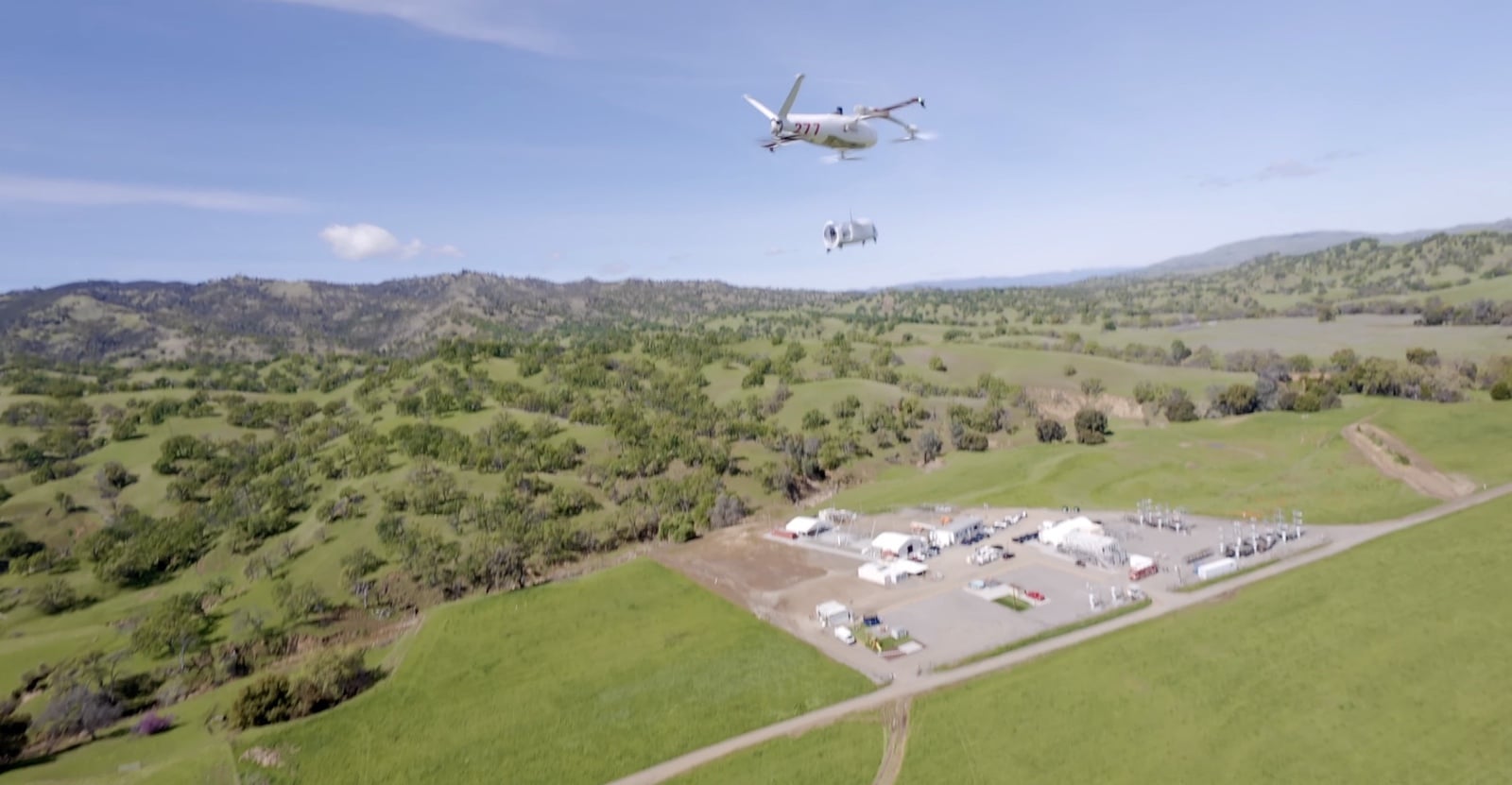 Aerial view of the hillside test range with an aircraft passing overhead.