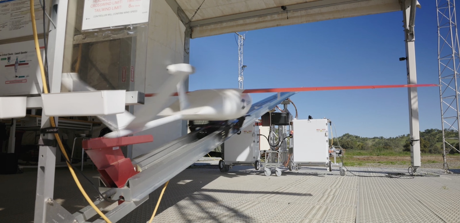 Zipline fixed-wing aircraft waits on its catapult rail inside an open bay.