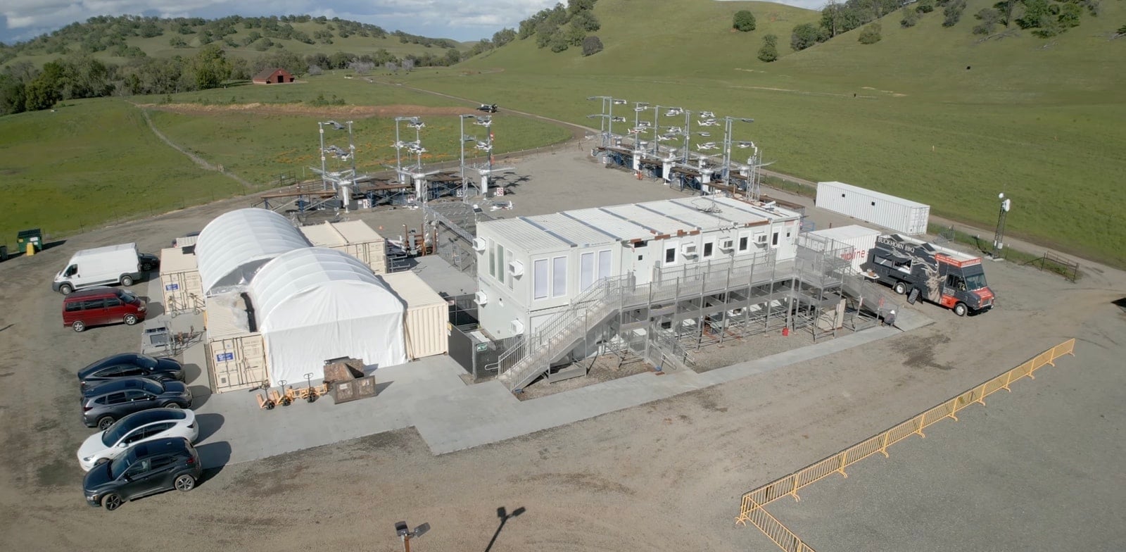 Overhead view of a Zipline hub with tents, containers and parked cars.