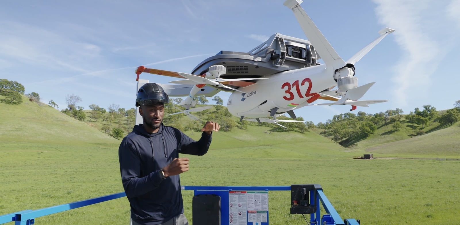 MKBHD stands beside a Zipline catapult as fixed-wing drone number 312 launches overhead.