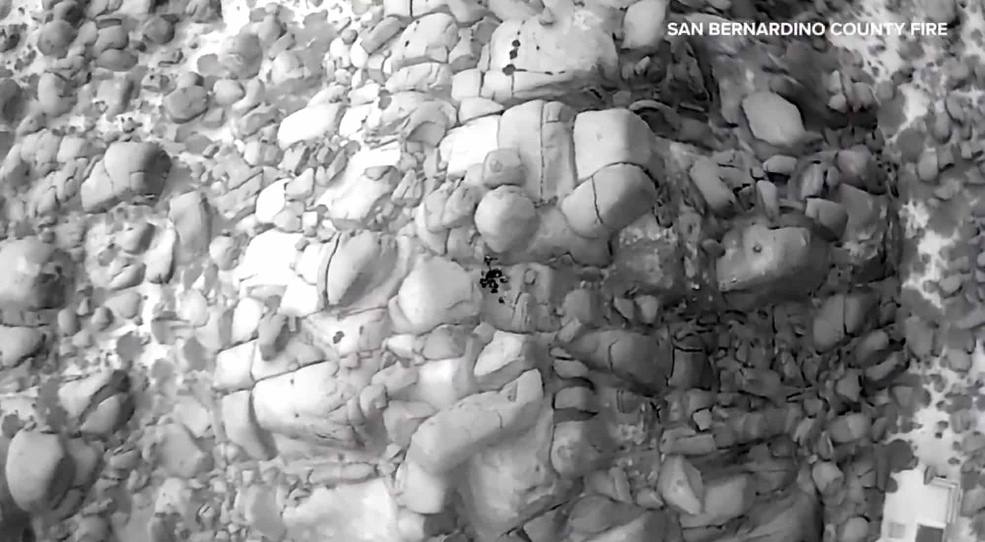 Straight-down thermal image of stacked boulders with a heat signature in a gap.