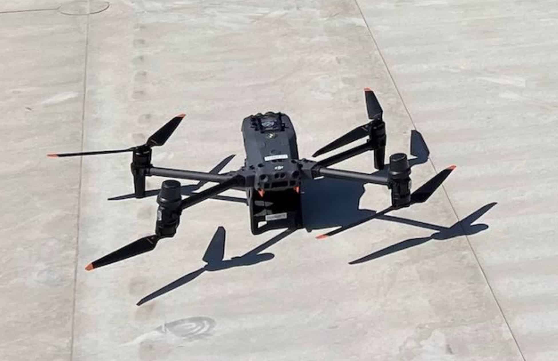 A large enterprise quadcopter sits ready on a concrete pad before launch.